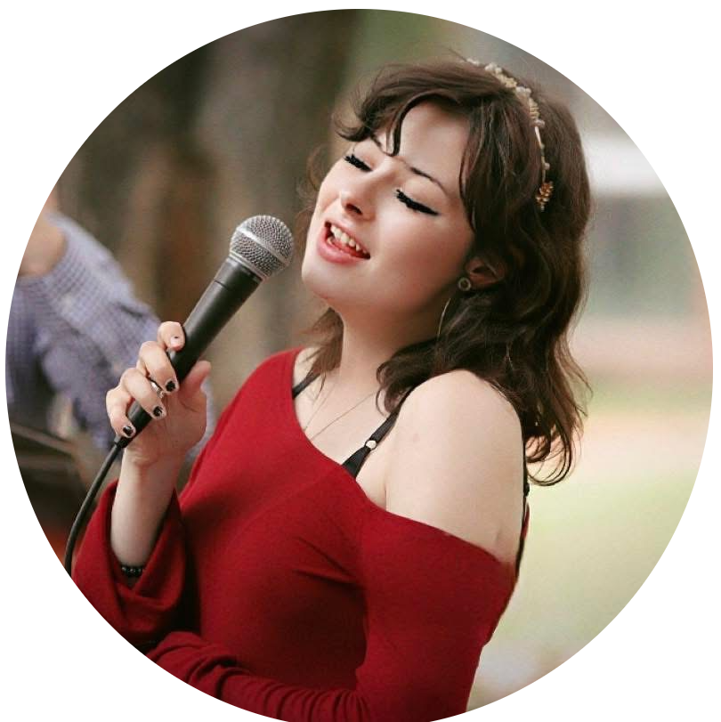 Kiera Sankey holding a microphone, wearing a red sweater, and singing.