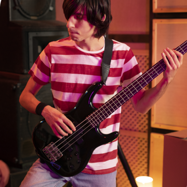 Teen student practicing bass guitar during a private music lesson in a professional studio environment.