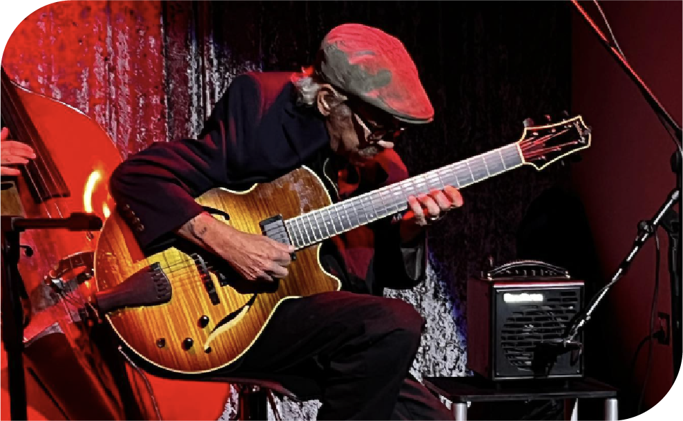 Professional jazz guitarist performing on stage with hollow-body electric guitar under red stage lighting at Philadelphia music venue