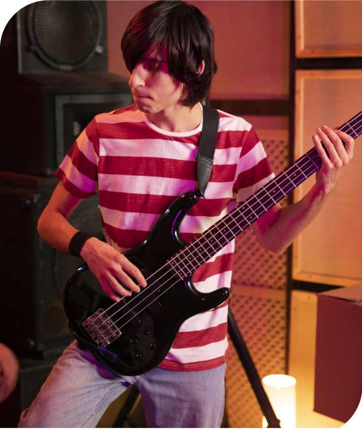 Teen student practicing bass guitar during a private music lesson in a professional studio environment.